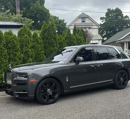 Gray Rolls-Royce SUV parked on suburban street
