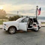 White Rolls-Royce SUV with open doors at sunset