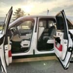 White luxury SUV with doors open at sunset