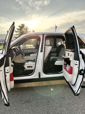 White luxury SUV with doors open at sunset