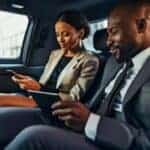 Two business professionals using devices in car