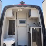 Interior view of a camper van with toilet and kitchenette.