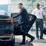 Businessman exiting luxury car at airport curbside