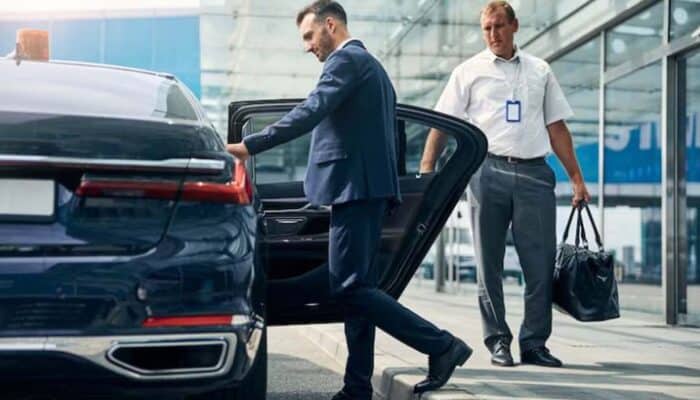 Businessman exiting luxury car at airport curbside