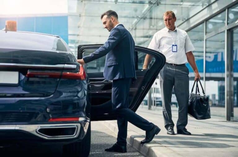 Businessman exiting luxury car at airport curbside