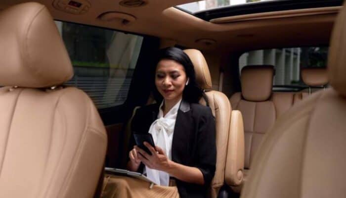 Businesswoman using smartphone in car backseat