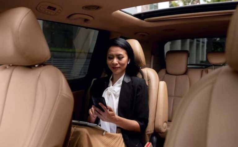 Businesswoman using smartphone in car backseat