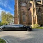 Black stretch limousine parked beside historic stone church