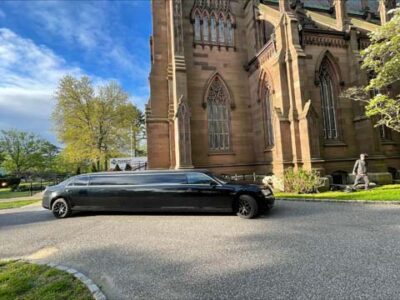 Black stretch limousine parked beside historic stone church