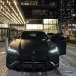 Black Lamborghini SUV parked outside luxury building at night
