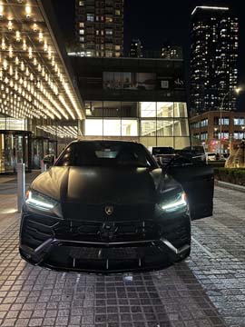 Black Lamborghini SUV parked outside luxury building at night