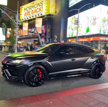 Matte black Lamborghini Urus in Times Square at night