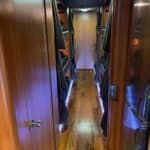 Narrow wooden hallway inside luxury RV with mirror.