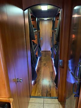 Narrow wooden hallway inside luxury RV with mirror.