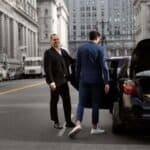Two businessmen beside black car on city street