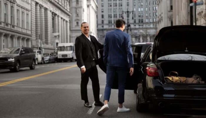 Two businessmen beside black car on city street