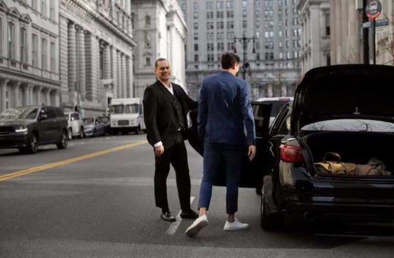 Two businessmen beside black car on city street