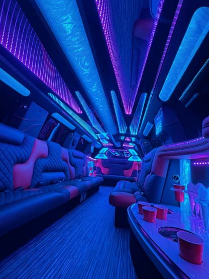 Neon-lit luxury limousine interior with seating and red cups