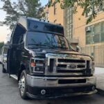 Black Ford shuttle bus parked beside brick building