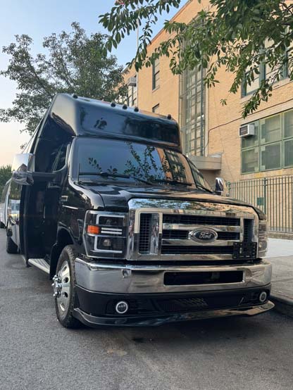 Black Ford shuttle bus parked beside brick building