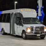 White shuttle bus parked at a gas station at night