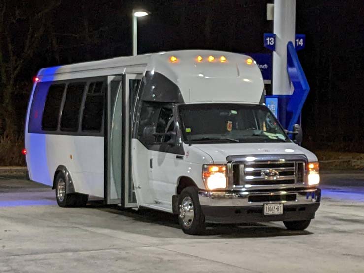 White shuttle bus parked at a gas station at night