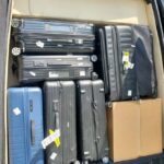 Car trunk packed with multiple suitcases and box