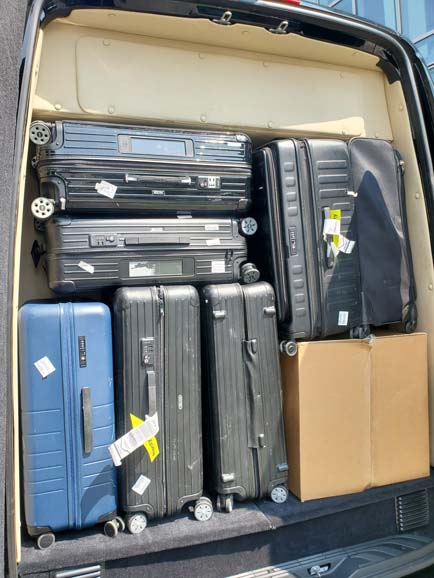 Car trunk packed with multiple suitcases and box