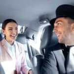 Smiling chauffeur driving woman in back seat