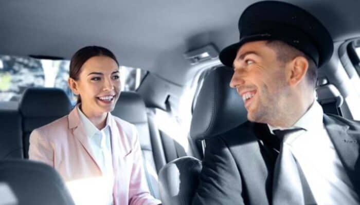 Smiling chauffeur driving woman in back seat
