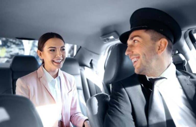 Smiling chauffeur driving woman in back seat