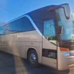 Silver coach bus parked outdoors in sunlight
