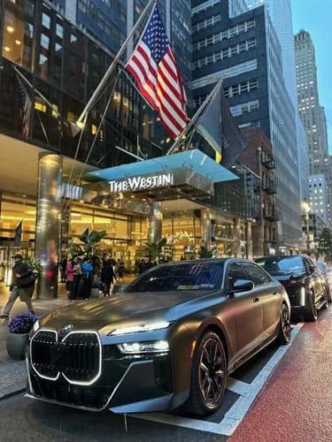 BMW sedan parked outside The Westin with American flags