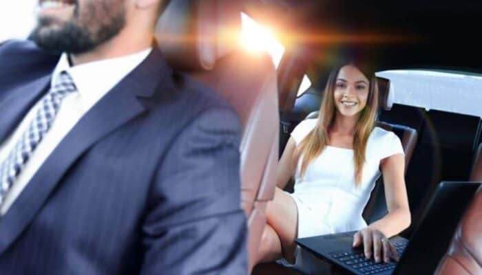 Woman using laptop in backseat of chauffeured car