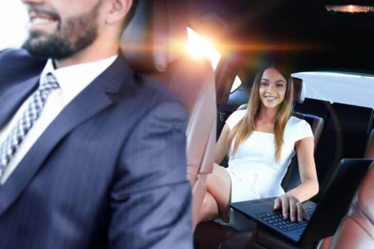 Woman using laptop in backseat of chauffeured car