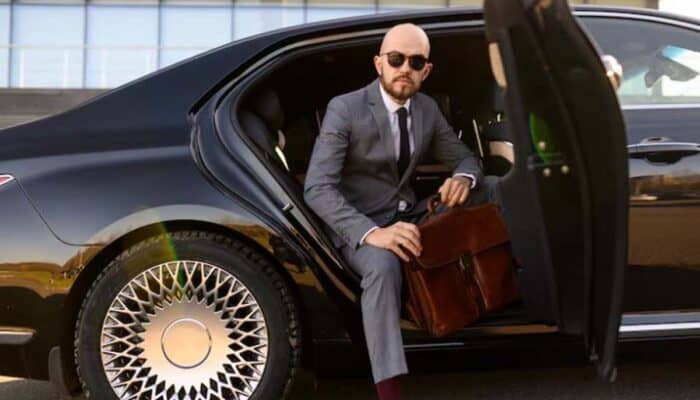 Businessman in suit exiting luxury car with briefcase