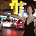 Woman hailing taxi on neon-lit city street