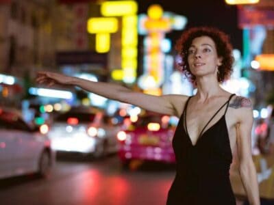 Woman hailing taxi on neon-lit city street