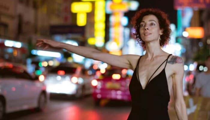 Woman hailing taxi on neon-lit city street