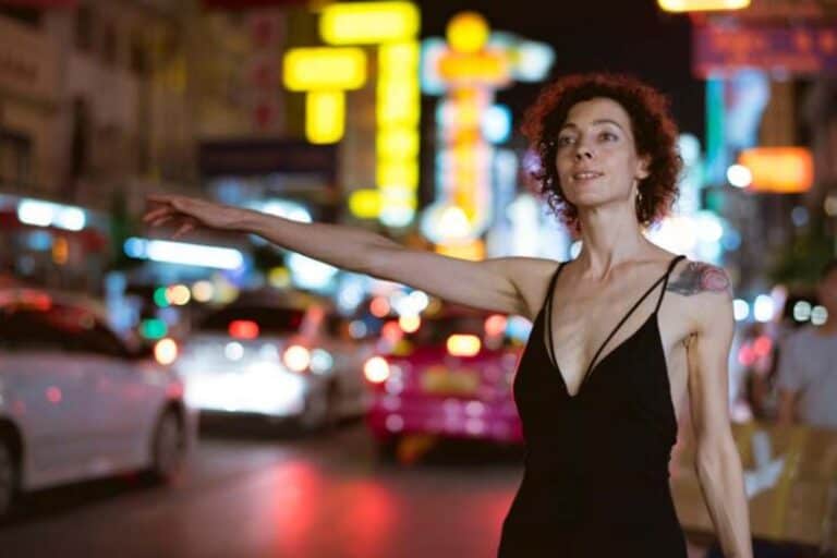 Woman hailing taxi on neon-lit city street