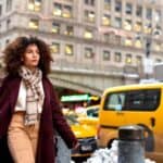 Woman walking in city street near yellow taxi
