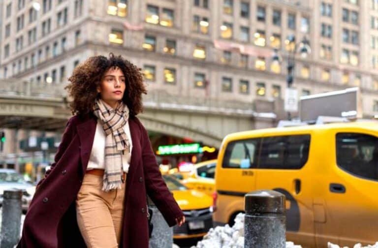 Woman walking in city street near yellow taxi
