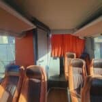 Empty coach bus interior with brown seats and orange curtain