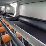 Modern train interior with orange seats and luggage racks