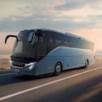 Modern coach bus driving on highway at sunset