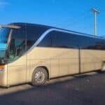 Beige coach bus parked under clear blue sky