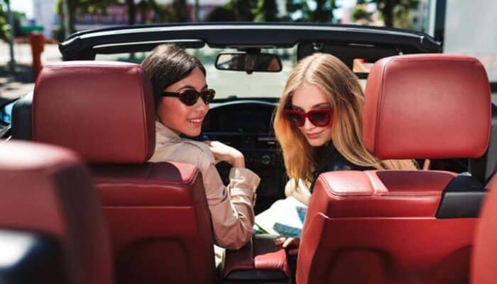 Two women in convertible with red interior