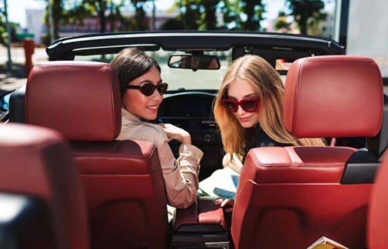 Two women in convertible with red interior