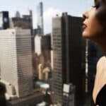 Woman overlooking city skyline from high-rise balcony