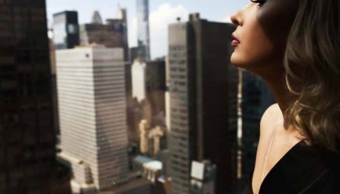 Woman overlooking city skyline from high-rise balcony